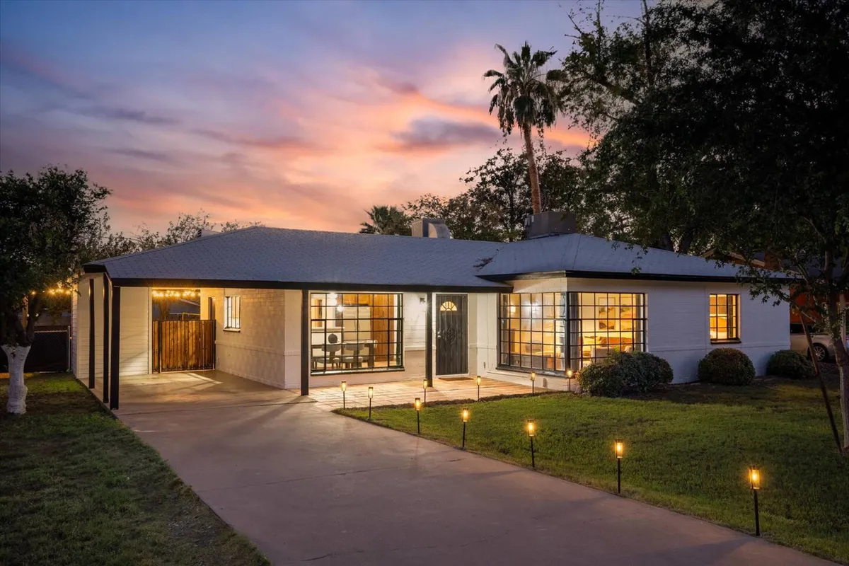 The landscaped front yard and spacious porch of the home are showcased here, with large windows letting in natural light and a sense of openness. The inviting exterior is perfect for gatherings, quiet mornings, or unwinding after time spent on the golf course.