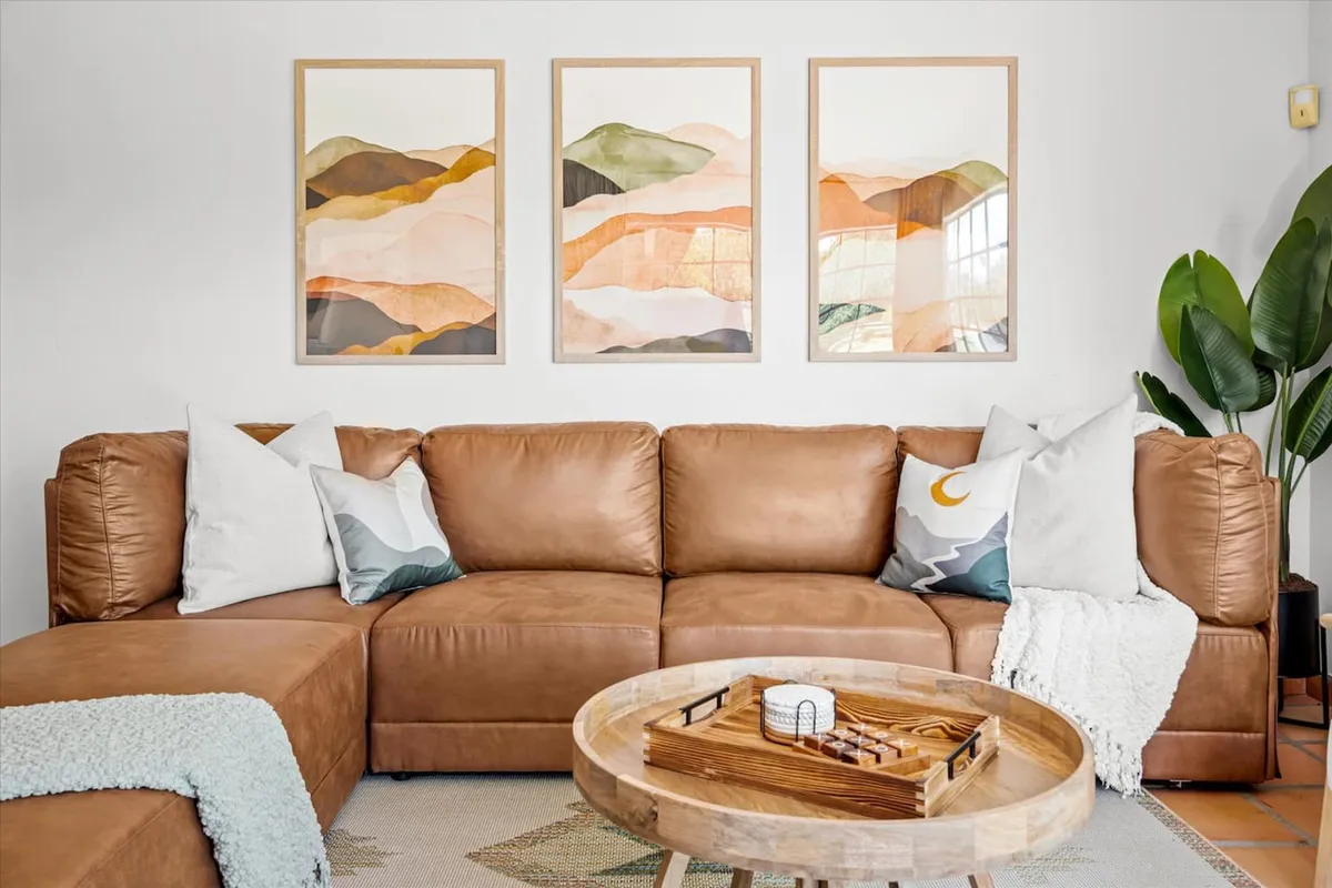 A modern living room with a luxurious leather sectional sofa, contemporary artwork adorning the wall, and a chic coffee table as the centerpiece. The setup is ideal for both relaxation and socializing, with a sophisticated yet comfortable vibe.